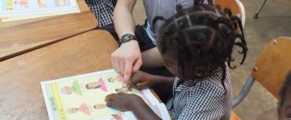 A Projects Abroad volunteer helps with homework during her childcare volunteering in Jamaica for groups. A volunteer works with children on English lessons in Jamaica with a group.